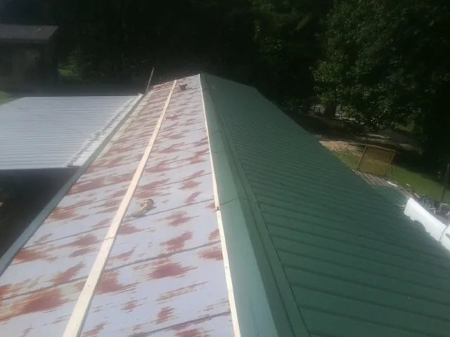 Old rusted panels beside newly installed green metal roofing — Wind Damage Roof Repair by Roofing Brothers in Coopersburg
