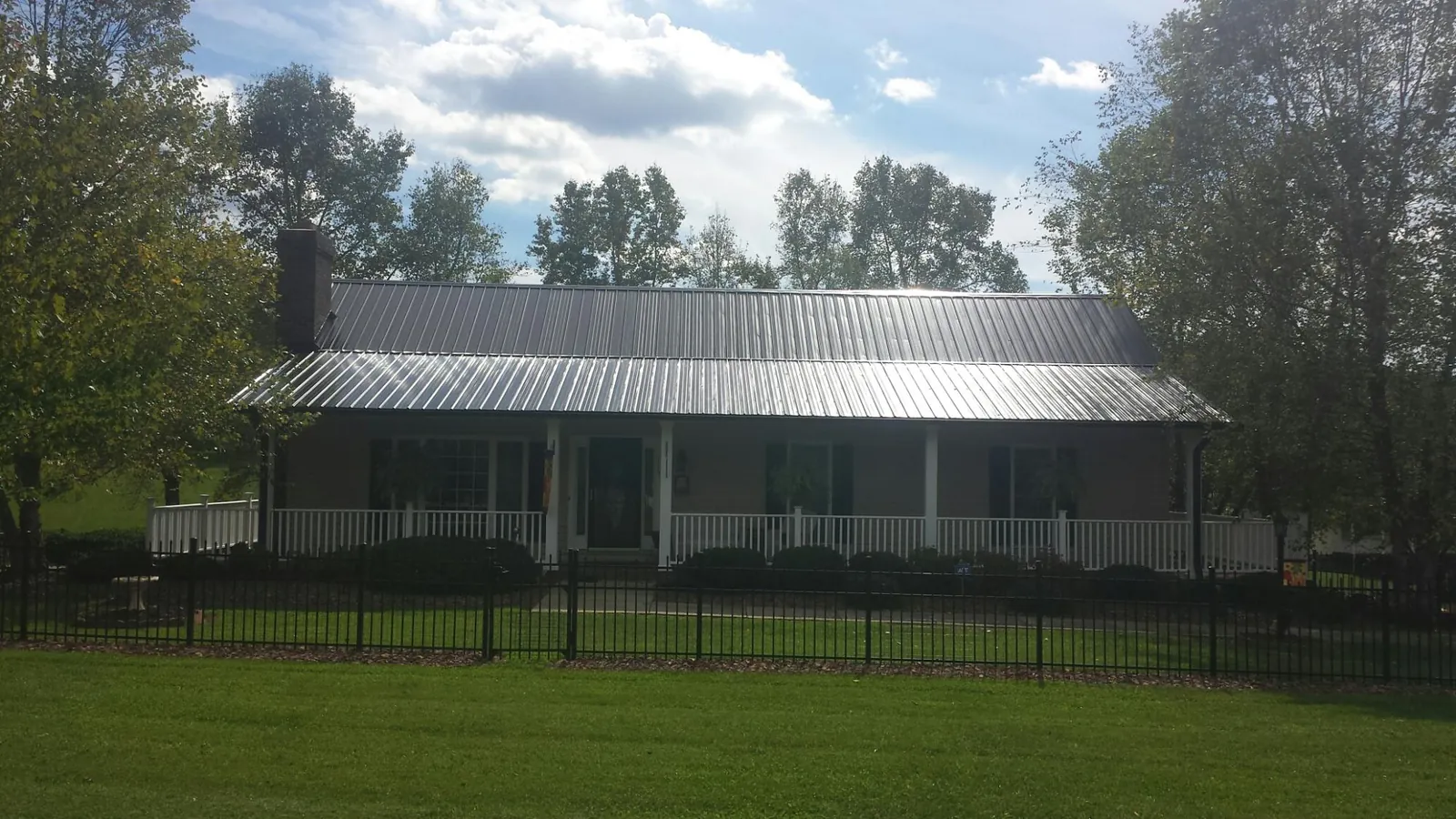 Gray metal roof on a brick ranch with a full width front porch — Gutter Guard Installation work by our crew in Coopersburg