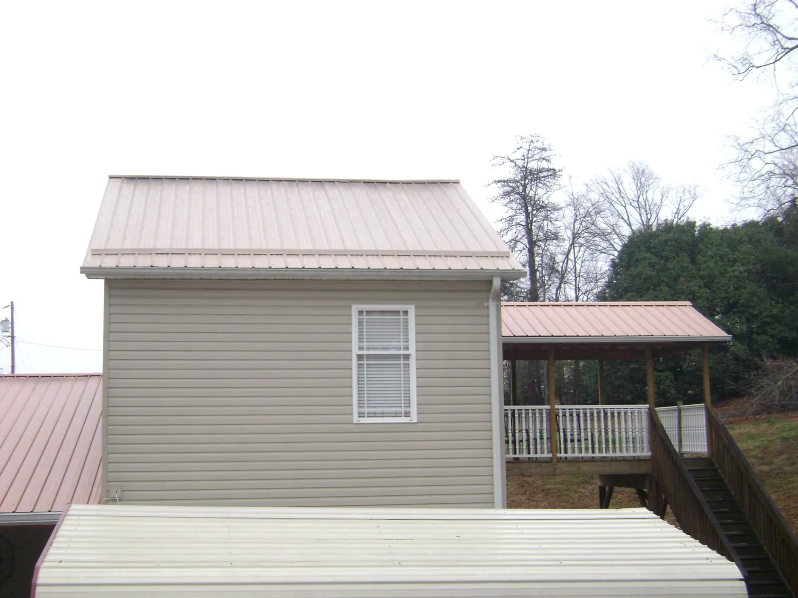Tan metal roofs on a two story addition and attached porch, from a Roof Replacement job in Coopersburg