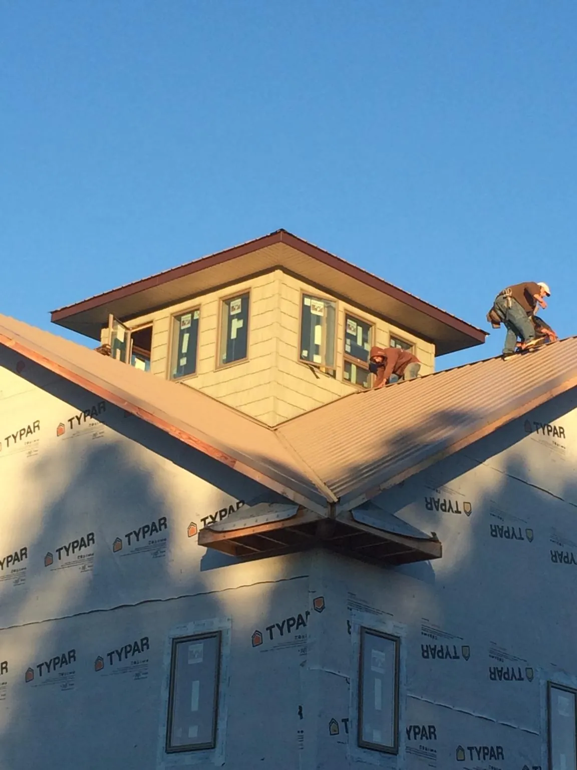 Roofers working around a rooftop cupola on a new metal roof at sunset — Roof Waterproofing in Coopersburg by Roofing Brothers